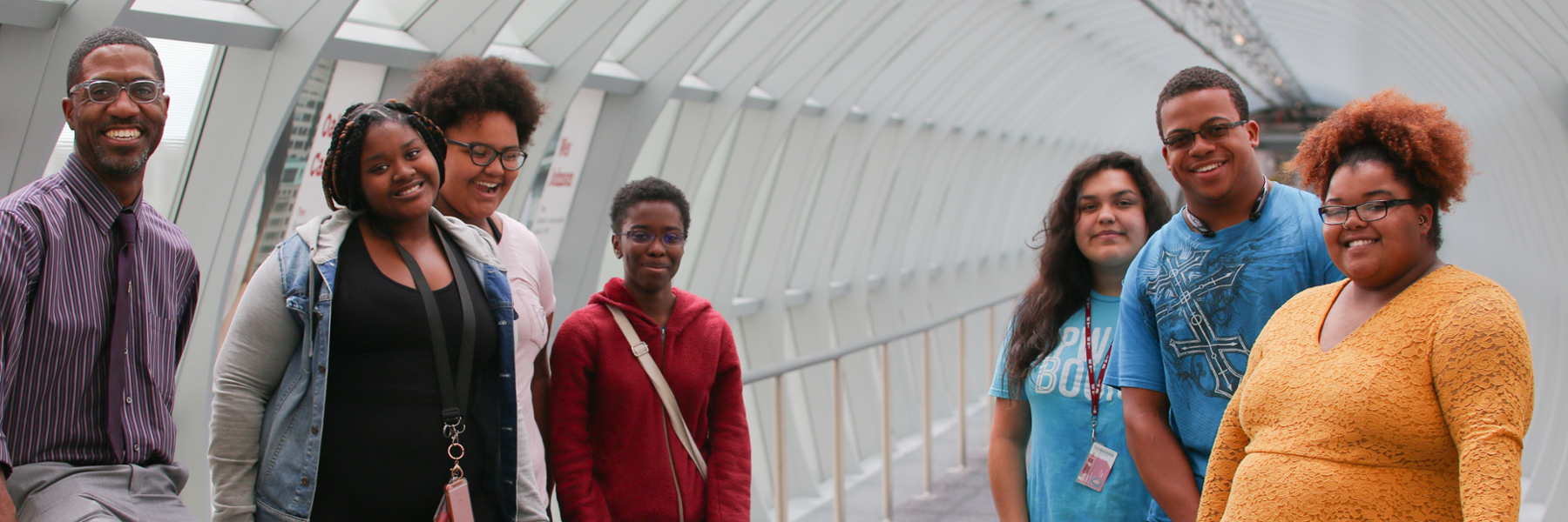 Some students and a professor standing and smiling in skywalk.