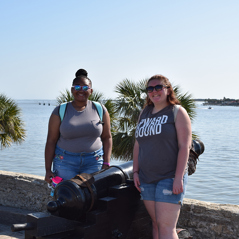 Two Upward Bound students standing by a cannon.